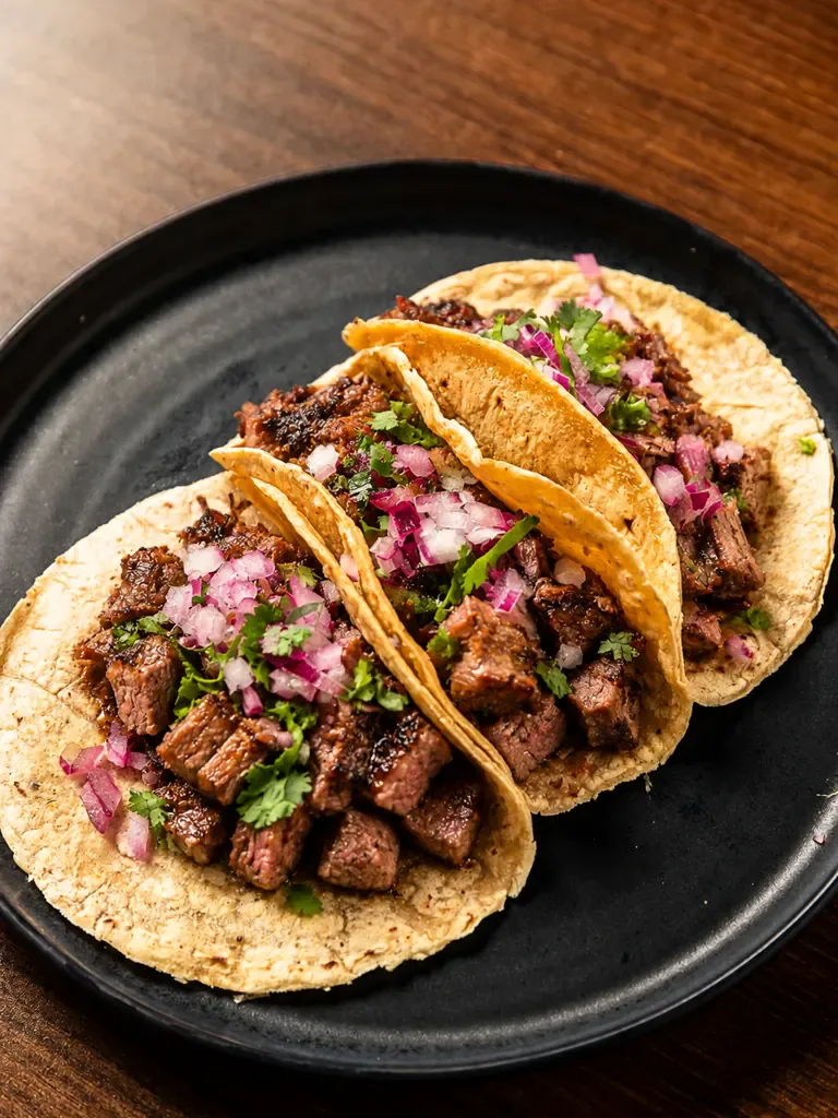 Tacos de arrachera a la parrilla con cebolla morada y cilantro en Piñata Cantina