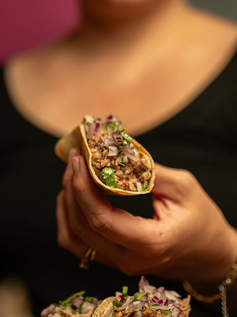 Taco de carnitas en la mano en Piñata Cantina