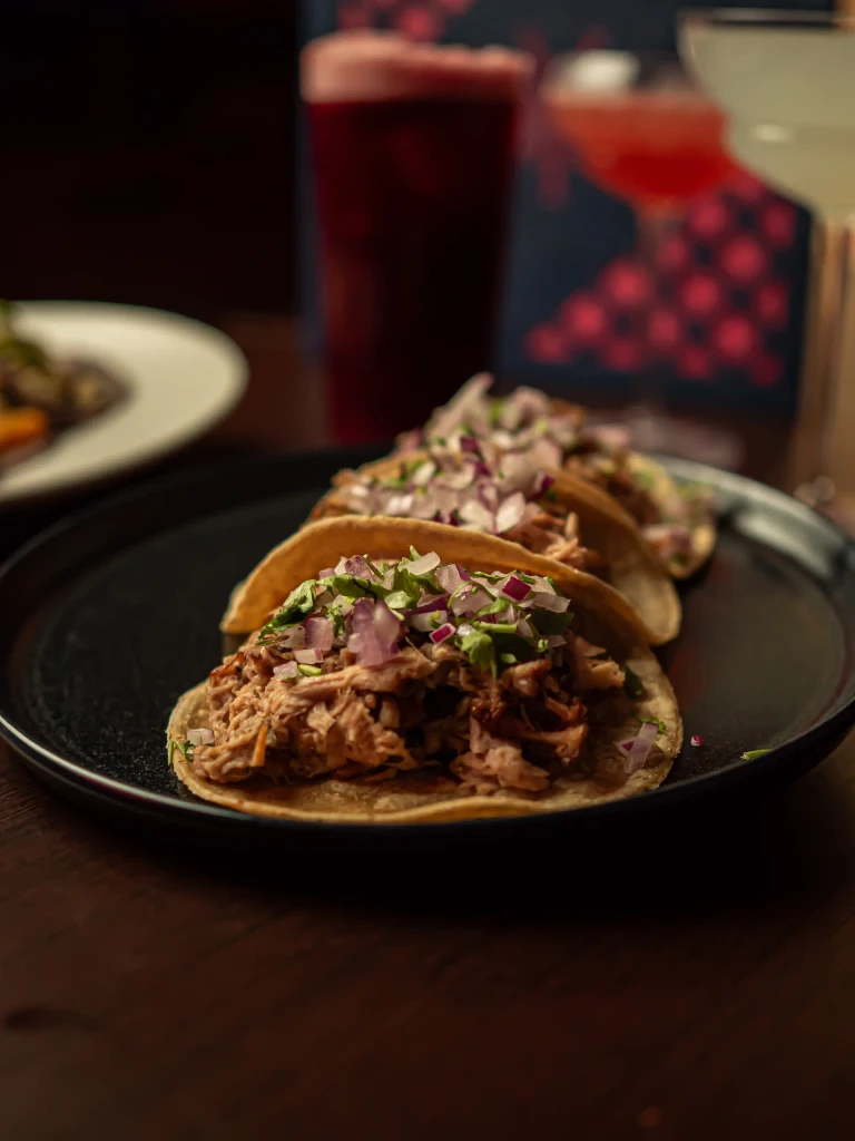 Tacos de carnitas con cebolla morada y cilantro en Piñata Cantina